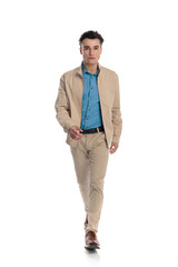 Fototapeta premium confident fashion man in beige jacket looking forward and stepping