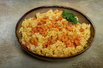 risotto with shrimp, in a bowl, on a textured surface, with a side dish of fresh coriander, homemade, no people,