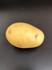 Single fresh potato displayed on a black background, highlighting its natural texture and earthy tones. Ideal for food, farming, or organic product themes.