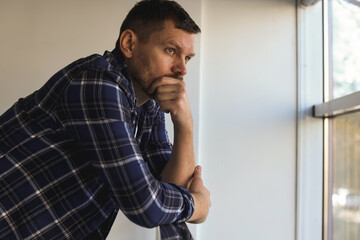 Depressed man near window in building. Mental health problem