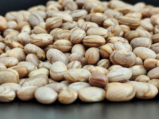 An abundant amount of dry beans scattered on a dark surface, highlighting their natural textures and earthy colors, perfect for food, agriculture, or rustic-themed concepts.