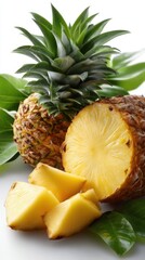 A still life with pineapple, cut into pieces, with green leaves around the fruit on a white background.