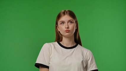 Teenage girl posing at camera with mad upset frustrated face, negative expression, isolated on chroma key green screen studio background mockup.
