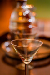 Selective focus on a crystal martini glass rim with a gleaming decanter softly blurred behind