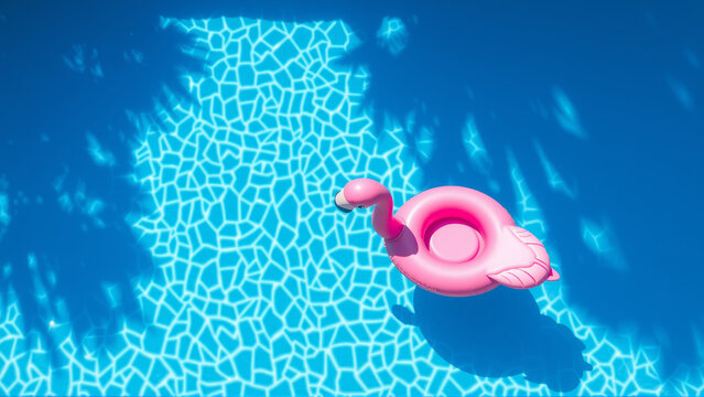 Inflatable pink flamingo circle swimming in the pool - Powered by Adobe
