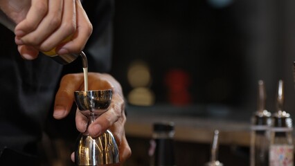 Closeup mixing hand bartender holding jigger to measure juice into shaker design preparation for...