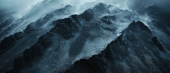 Rugged mountain range dominates scene under misty, overcast sky emphasizing erosion, stark contrasts.