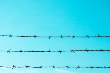 Barbed wire fence pattern against blue sky