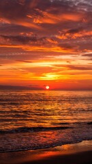 Obraz premium Vibrant sunset over beach with fiery sky and golden reflections on ocean