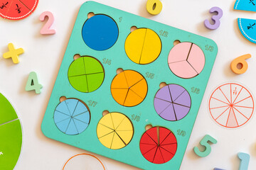 Colorful wooden fraction puzzle with circular pieces for educational play on a white background...