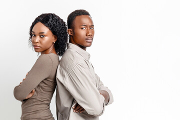 Sad african american man and woman with arms crossed staying back to back over grey studio background, thinking about breaking up after fight. Upset black couple posing together at studio