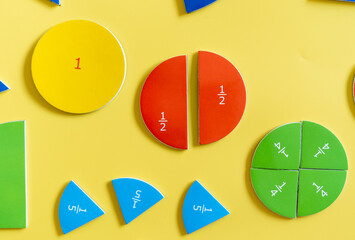 Colorful math fraction puzzles arranged on a bright yellow background showcasing different fraction...
