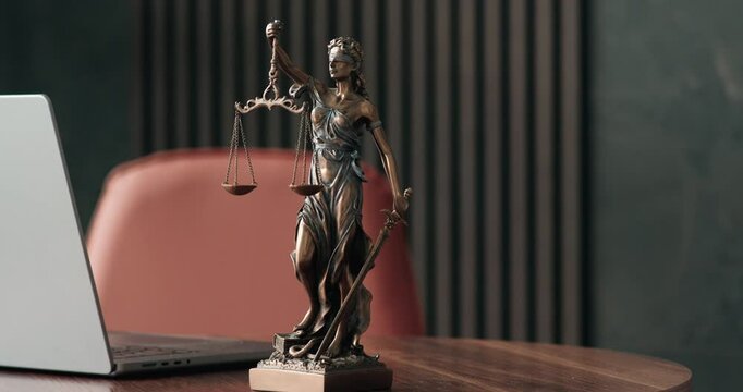 Lawyer's office. Statue of justice with scales and a laptop in a modern office cubicle. Concept of legal law, counseling and concept of justice.