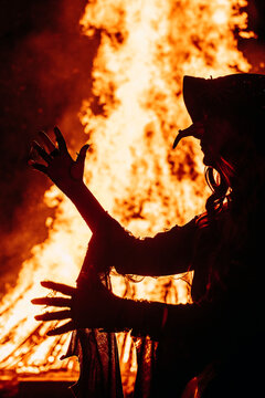 Walpurgisnacht,, Maifeuer oder Hexenfeuer. Eine Hexe posiert vor einem gro&szlig;en Lagerfeuer / Scheiterhaufen. 
