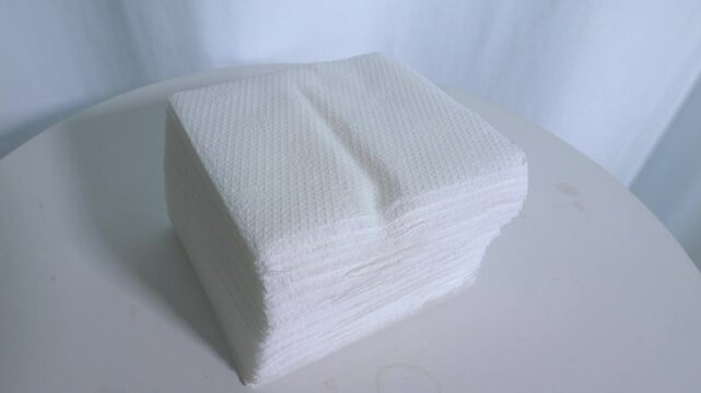 Paper napkins on a turntable. White napkins on a white background are spinning. Slow motion.