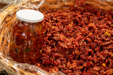 Sun-dried red cherry tomatoes in a wicker basket with price in a street food market in Bari, close up