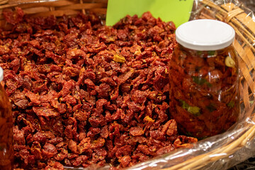 Sun-dried red cherry tomatoes in a wicker basket with price in a street food market in Bari, close up