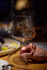 Champagne tasting, Wine glasses are on the table, stylish table setting, A man's hand holds a beautiful elegant glass with rose sparkling wine, an intimate light, a plate with oysters and lemon