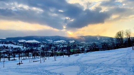 A Beautiful and Serene Winter Landscape Featuring a Vibrant Sunset Over SnowCovered Hills