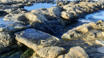Rocky shoreline with tidal pools and gentle ocean waves  