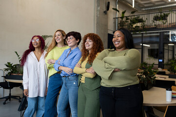Five businesswomen smiling with arms crossed in coworking space