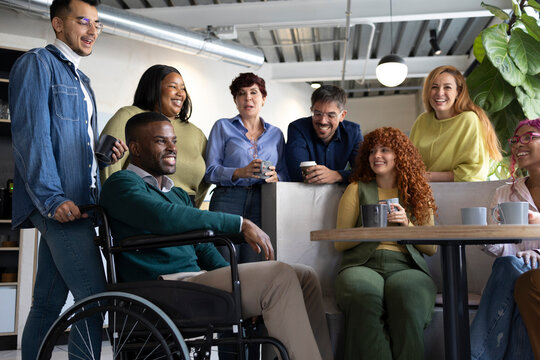 Coworkers enjoying a coffee break, chatting and laughing together in an inclusive workplace - Powered by Adobe