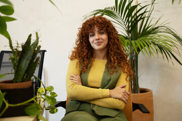 Confident businesswoman sitting with crossed arms in green office