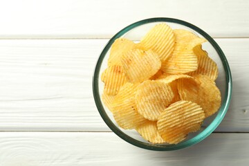 Tasty potato chips on white wooden table, top view. Space for text