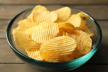 Tasty potato chips on wooden table, closeup