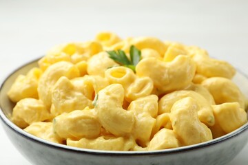 Delicious pasta with cheese sauce in bowl on table, closeup