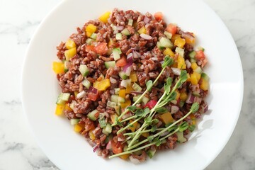 Tasty salad with brown rice on white marble table, top view