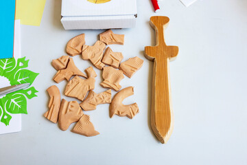 Unbaked clay pieces and a finished wooden sword toy are displayed  on the table on the flea  market