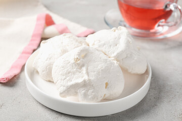 Delicious homemade meringue cookies and tea on gray table, closeup