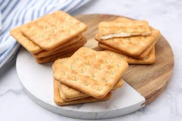 Tasty salty crackers on white marble table, closeup