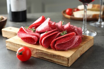 Slices of delicious sausage with thyme served on grey table, closeup