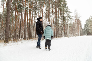 Naklejka premium Dad and daughter walking and having fun in snowy winter forest