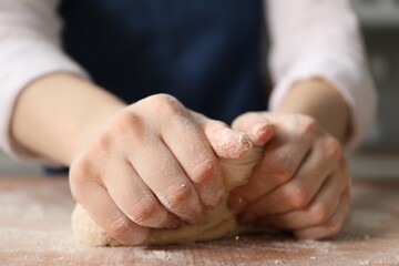Making khinkali. Woman kneading dough at table in kitchen, closeup