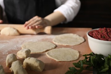 Woman making khinkali. Pieces of dough on table, closeup