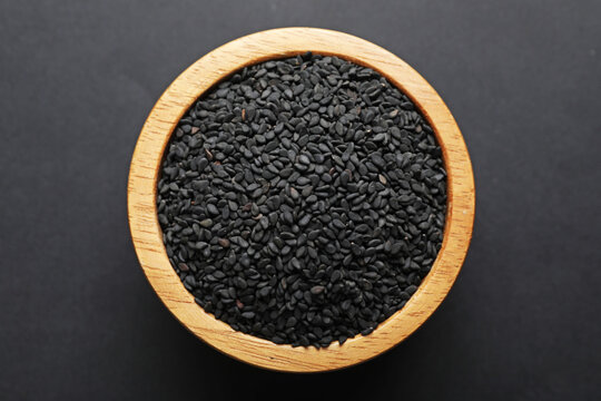 Aromatic black caraway in bowl on dark table, top view
