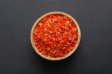 Dried carrots in bowl on dark table, top view