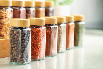 Many different aromatic spices in jars on table indoors, closeup