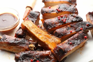 Delicious pork ribs and sauce on parchment paper, closeup