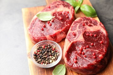 Pieces of raw beef meat and spices on gray table, closeup