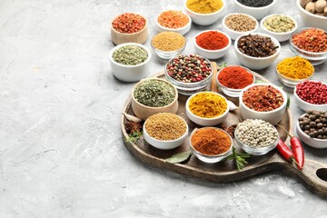 Different aromatic spices in bowls on grey table, space for text