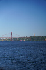 Fototapeta premium Scenic View of Suspension Bridge Cargo Ship and Monument on Calm Water