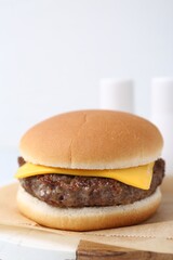 Tasty cheeseburger on white table, closeup. Space for text