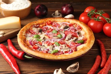 Tasty pizza with smoked sausages and ingredients on wooden table, closeup