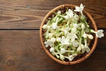 Wicker bowl with jasmine flowers on wooden table, top view. Space for text