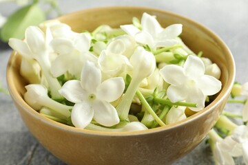 Beautiful jasmine flowers in bowl on table, closeup