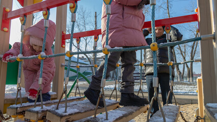 Grandfather with grandchildren playing on the playground on a cold winter day
